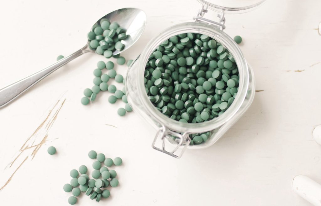 Green spirulina algae pills in the jar, taken from above.